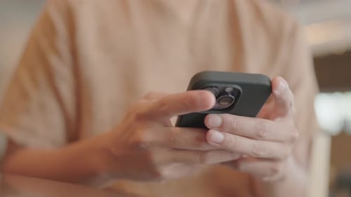 Close-up of a man sitting and typing a message on his smartphone in the network chat app.