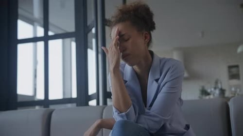 Woman Looks Stressed and Sad Sitting on Sofa