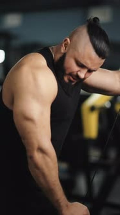 Muscular Athlete Executing Cable Triceps Pushdown Intensely Concentrating on Arm Muscle Definition
