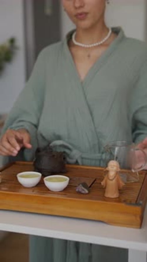 Woman Pours and Drinks Tea at Indoor Tea Ceremony