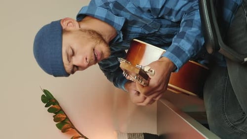 Young adult playing guitar indoors