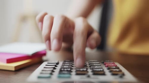 Hand press calculator to calculate income expenses and plans for spending money on home office.