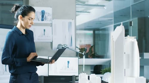Female Architectural Designer Works on a Laptop, Engineering New Building Model for the Urban Plan