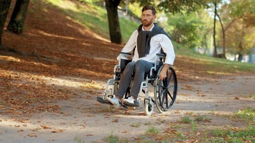Young Man Disabled in Wheelchair Rides in Park at Sunlight Paralysis Disability Handicapped Serious