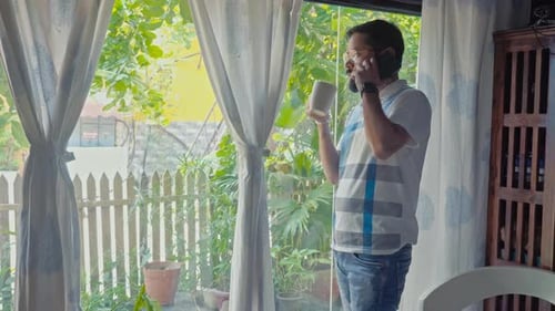 Man Talking on Phone While Drinking at Home