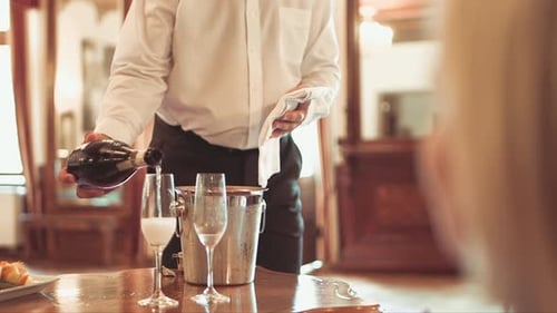 professional waiter pours champagne into two glasses