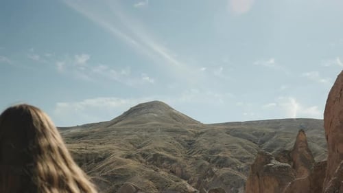 The young woman points into the distance towards a high mountain.