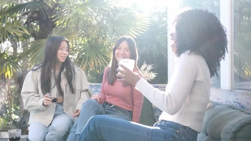 Three friends drinking and laughing outdoors