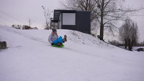 Wide Shot Slope with White Snow and Cheerful Teen Girl Passing on Green Sled
