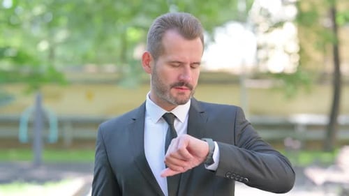 Man in Suit Checking Smart Watch Outdoors
