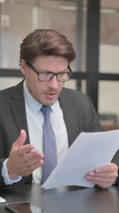 Businessman Feeling Upset while Reading Contract in Office, vertical