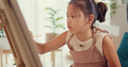 Young Girl Painting on Canvas in Bright Home