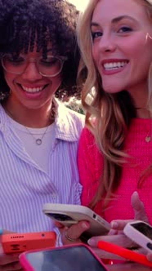 Friends Smiling and Using Cell Phones Together