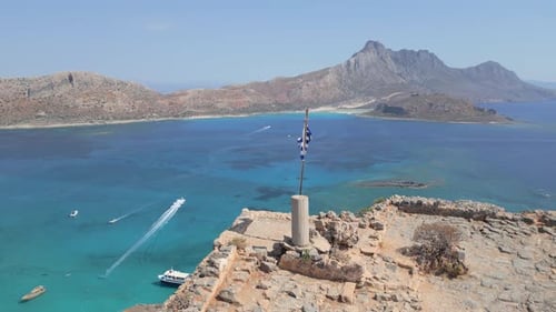 En orbite autour d'un drapeau grec au sommet de la colline de Gramvousa, avec la plage de Balos en arrière-plan