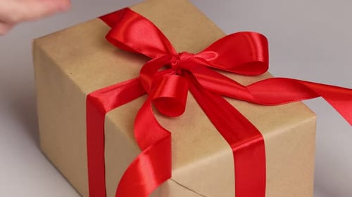 Hands Tying a Red Ribbon on Gift