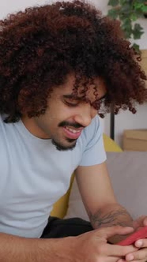 Smiling Man Using Smartphone Indoors on Couch