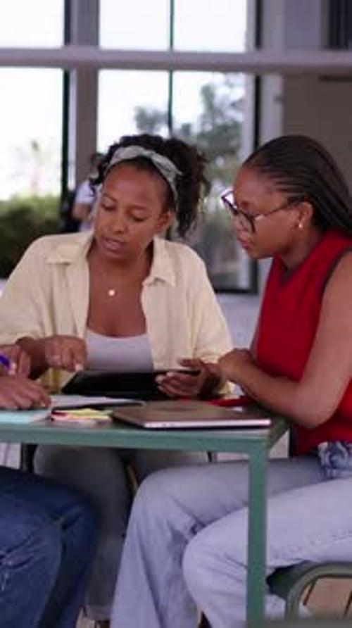 Young African American Women Friends Sitting on Table Inside University Campus Building