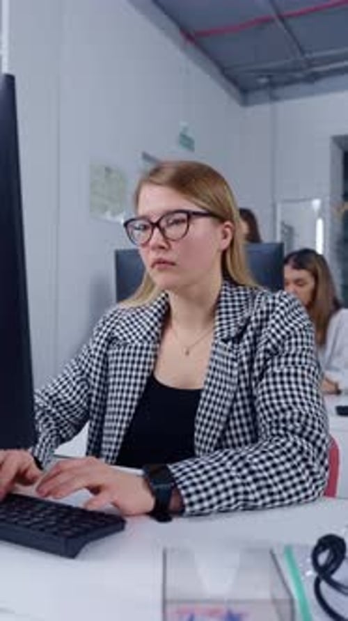 Focused Young Professional Woman Working at Computer in Modern Open Plan Office Environment Typing