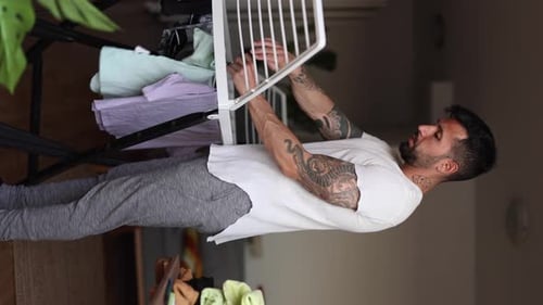 Man Hanging Clothes on White Drying Rack