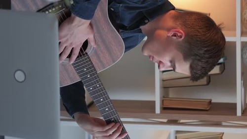 Young Adult Plays Acoustic Guitar in Bedroom