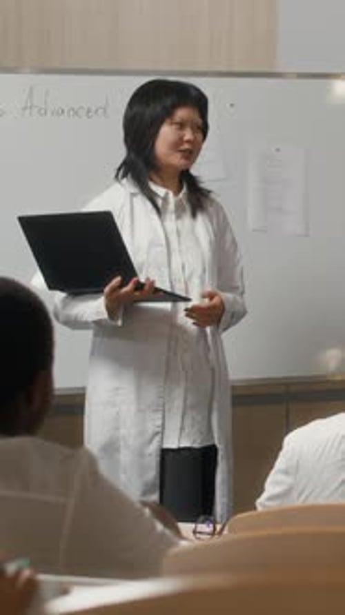 Asian Female Medical Student Presenting next to Board in College Auditorium