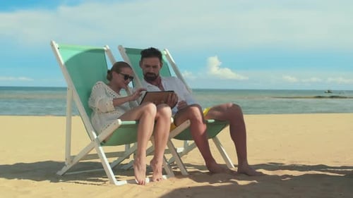 Couple Relaxing on Beach Using Tablet