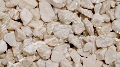 Sea Waves On Pebbles From the Beach Close Up Pure Water with Reflections Sunlight in Slow Motion