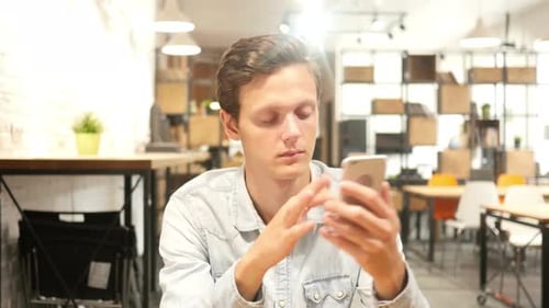 Young Man Using Smartphone in Office