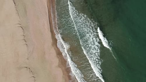 Kleine schöne Wellen treffen am Strand auf das Ufer - stationäre Luftaufnahme