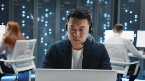 Man Works in Data Center Using Laptop and Headset