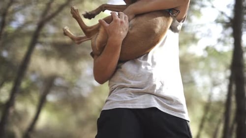 Man Holds Dog Lovingly Outdoors in Nature