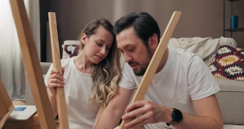 Serious Concentrated Woman and Man Trying to Decorate Furnish New Wooden Floor Lamp Moving in