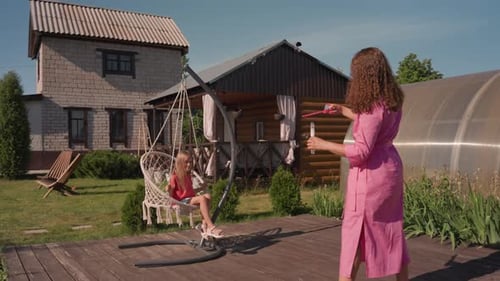 Woman and Girl Blow Bubbles in Backyard