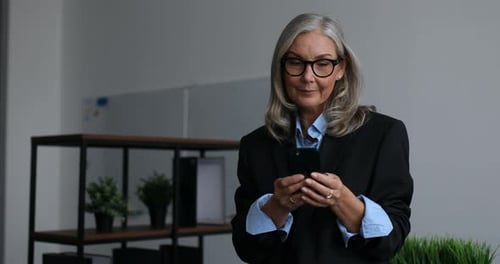 Elegant Mature Woman Uses Cell Phone in Office