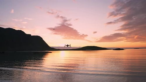 Drone Silhouette Over Calm Beach at Sunset