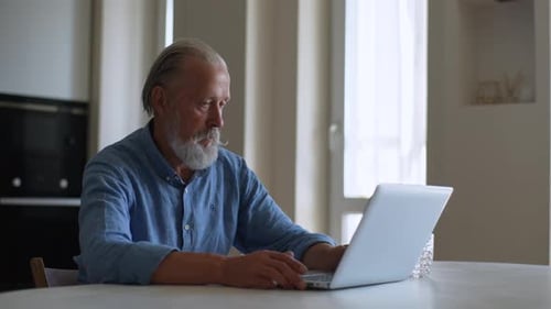 Senior Man Using Laptop Computer at Home