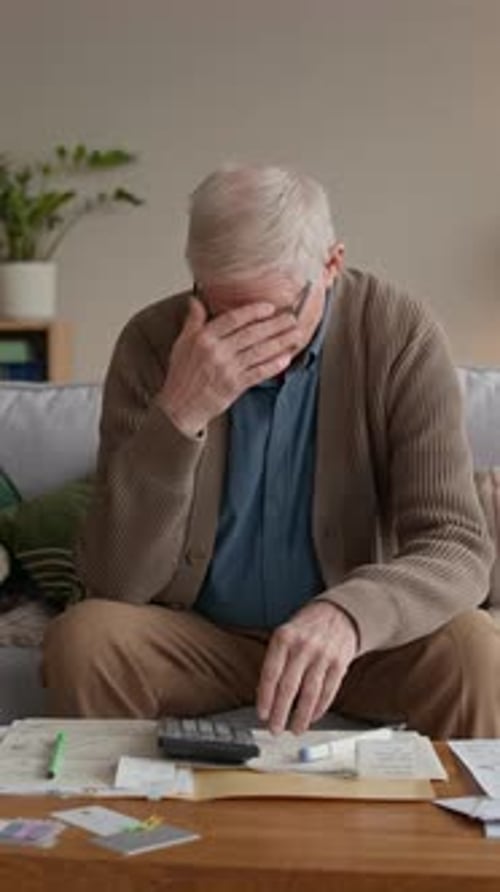 Distressed Senior Man Counting Expenses While Reviewing Bills at Home