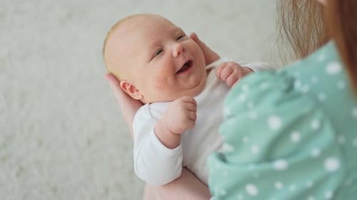 Happy Infant in Mother's Arms Smiling