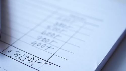 A Man Writes Payment Due in a Paper Form
