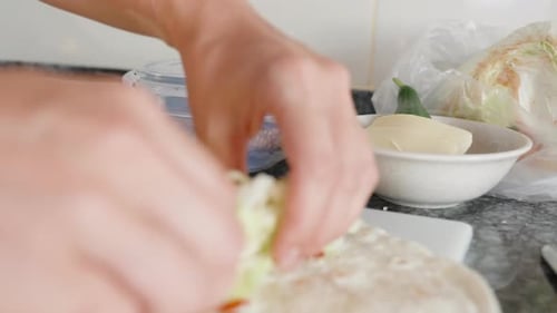 Cooking, I put cutted salad on top of the pita. I will do shawarma. Close-up in motion. Black stone