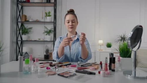 Woman Applies Lip Gloss in Home Setting
