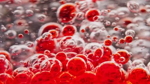 macro shot of red bubbles getting mixed in water, moving around