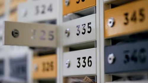 Closeup of Numbered Metal Mailboxes with Shallow Depth of Field Highlighting an Open Drawer Among