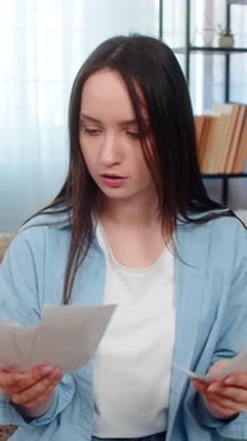 Young Woman Reviews Documents With Concerned Expression