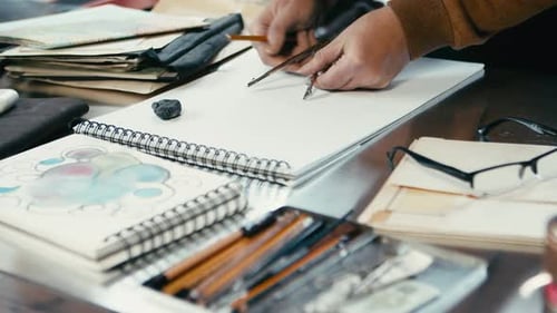 The designer uses a compass to measure distances on his sketch. Close-up shot