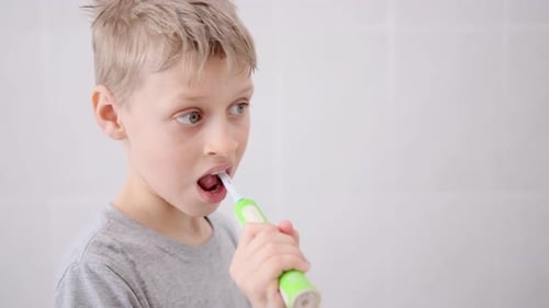 Child Brushing Teeth with Electric Toothbrush in Bathroom