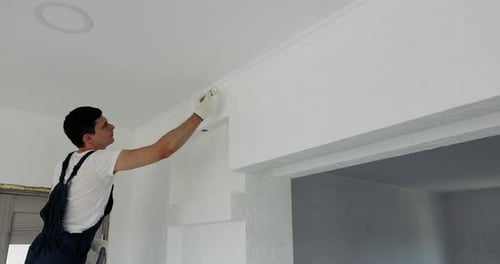 Man Painting Crown Molding in Bright Room