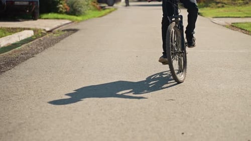 Sunny Suburban Street with Cyclist Showing Wheel and Shadow Environmentally Friendly Bicycle Courier