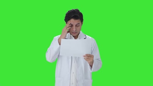 Stressed Indian doctor checking medical reports Green screen