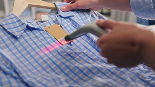 A Customer In A Shopping Store Scans The Tag Label Of A New Clothing Item With An Electronic Scanner